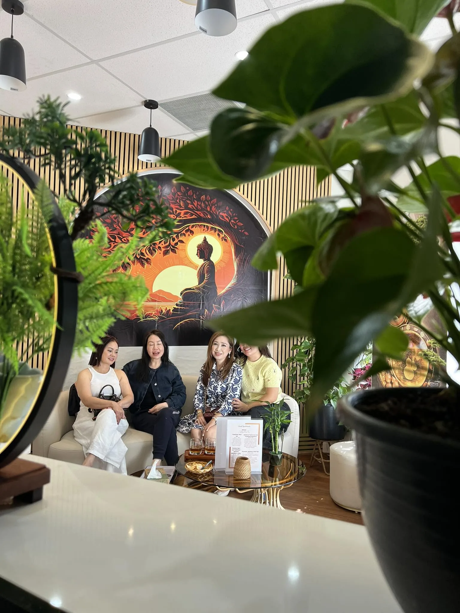 A group of four guests on the cream sofa, the Head Spa Rituals menu on the glass table