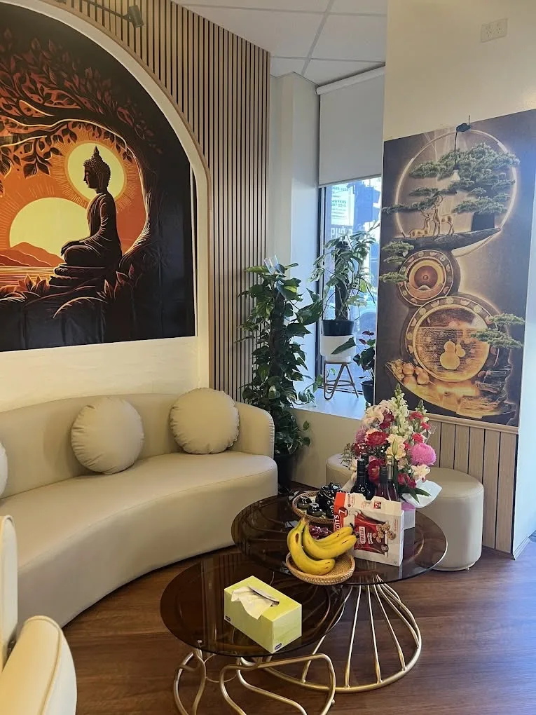 The lounge — cream sofa beneath the arched tree-of-life sunrise mural, warm honey timber, gold nesting tables