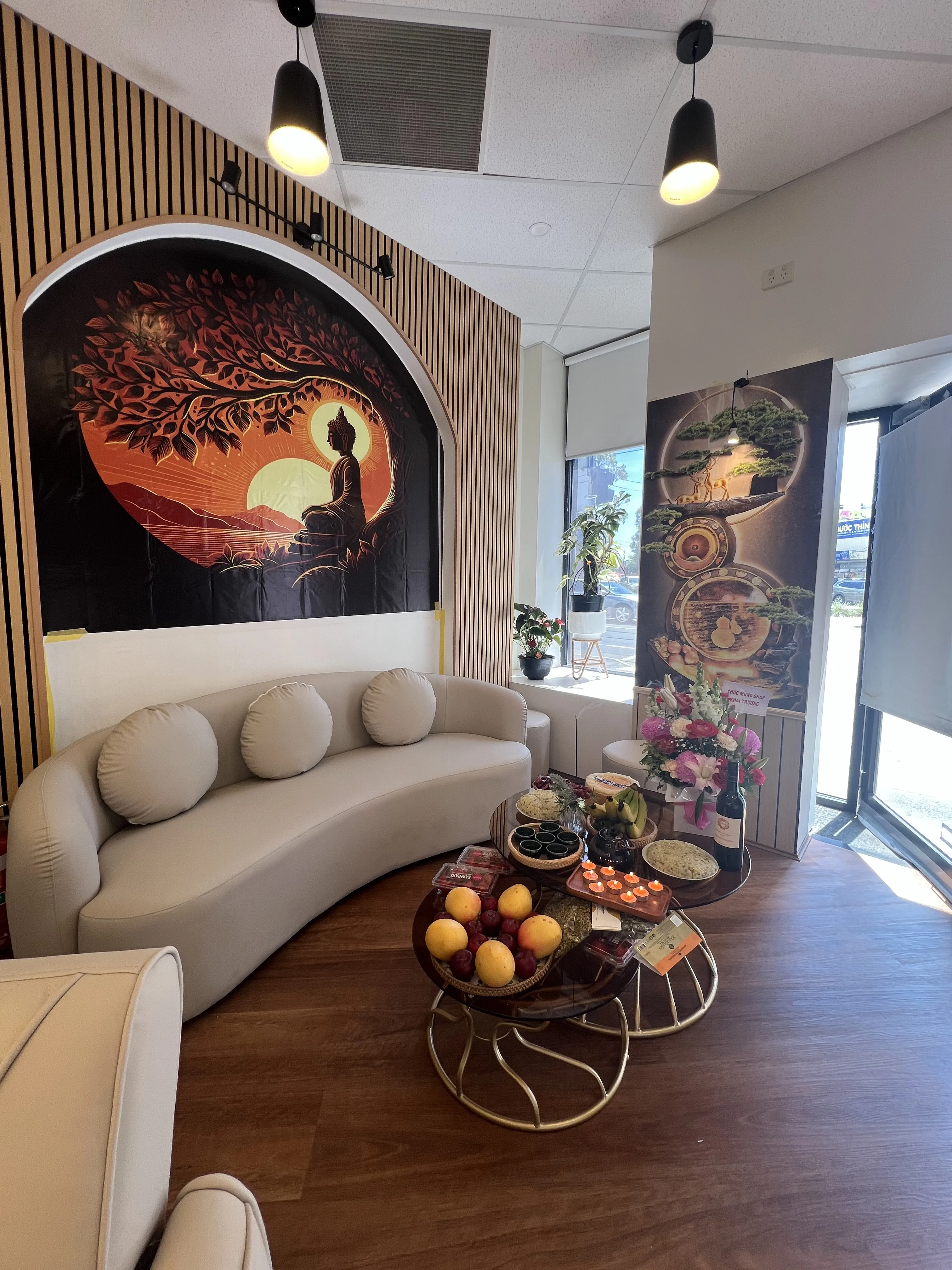 Reception lounge at 5/158 Barkly St — full-height oak batten wall, arched sunset mural, curved cream sofa and black pendant lamps