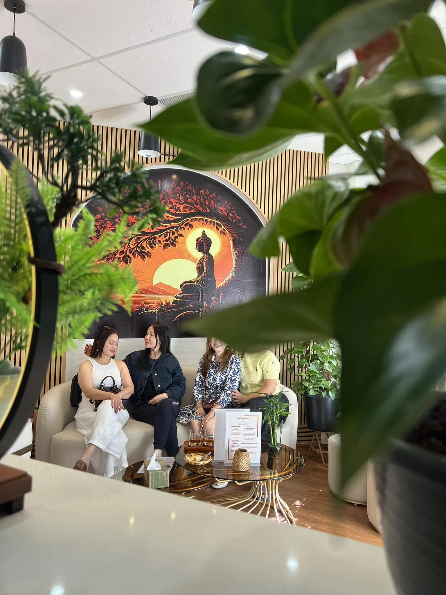 Four guests gathered on the cream sofa beneath the sunrise mural, warm company in the lounge