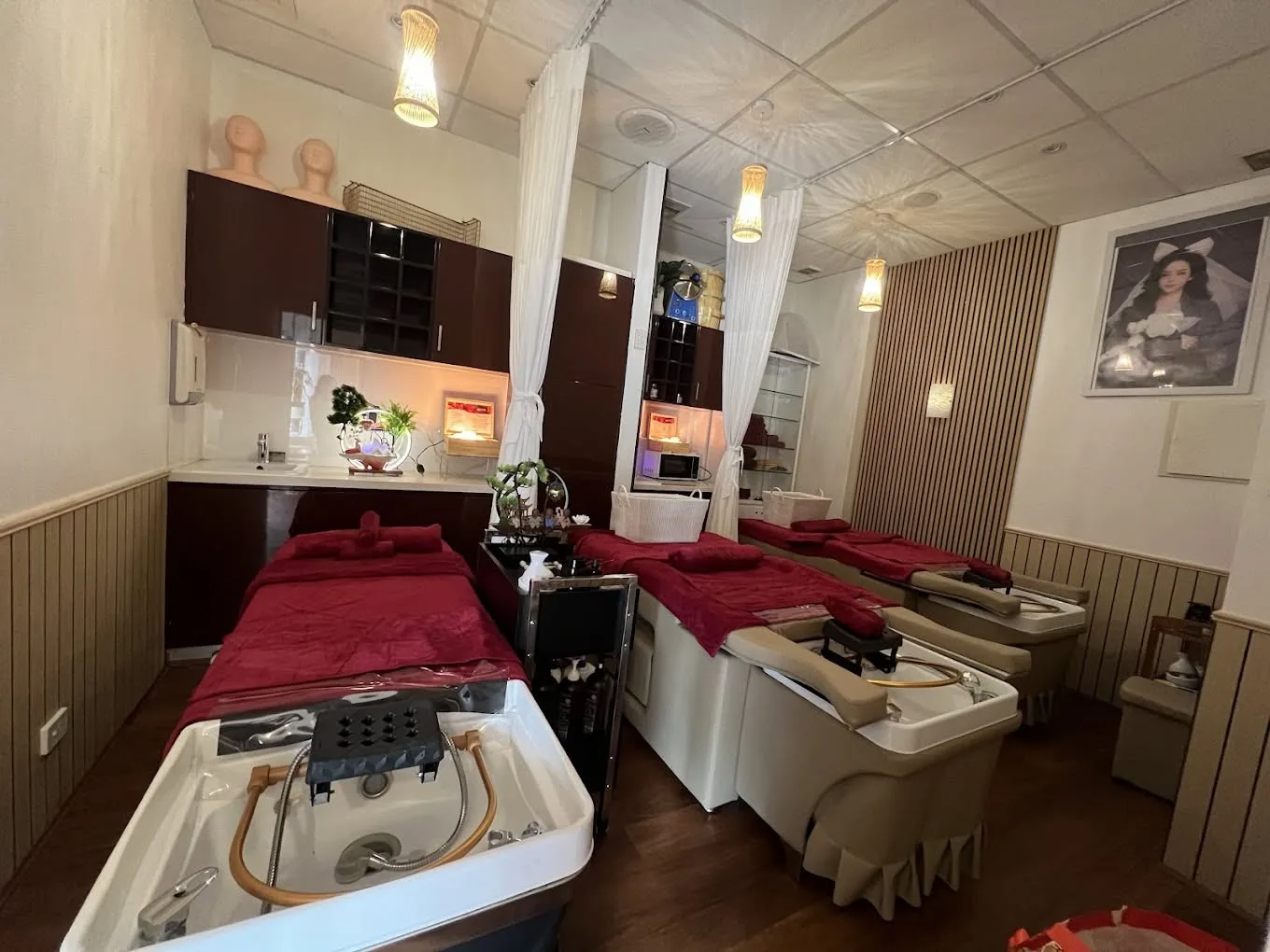 The head-spa treatment room — rows of deep-garnet wash beds with white ceramic basins and woven pendant lamps