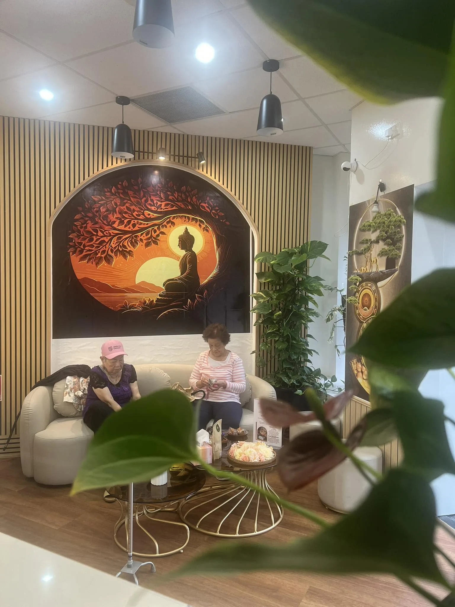 Two guests seated in the lounge with the tree-of-life mural behind them
